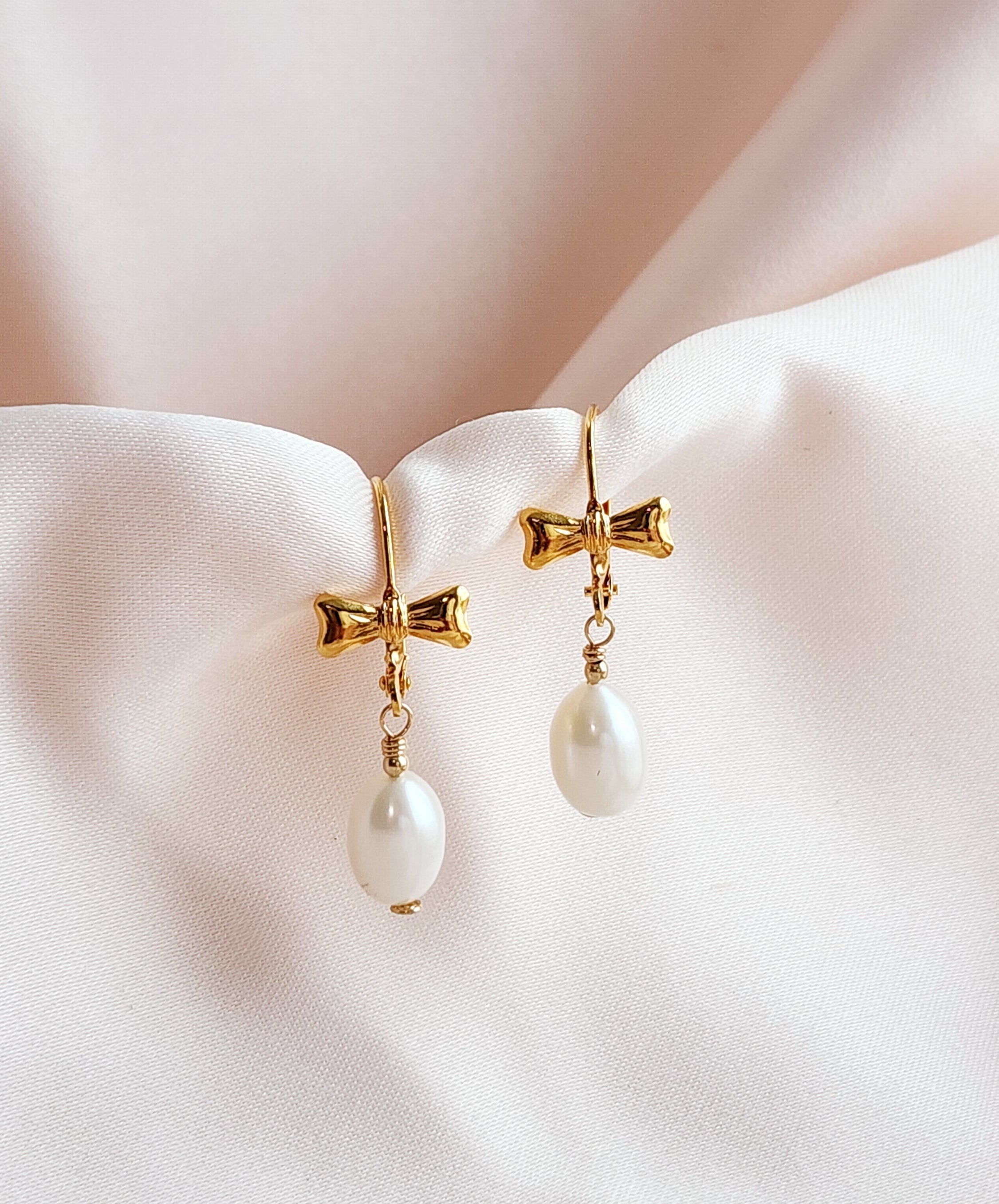 Front View of a pair of bow leverback earrings with teardrop pearls