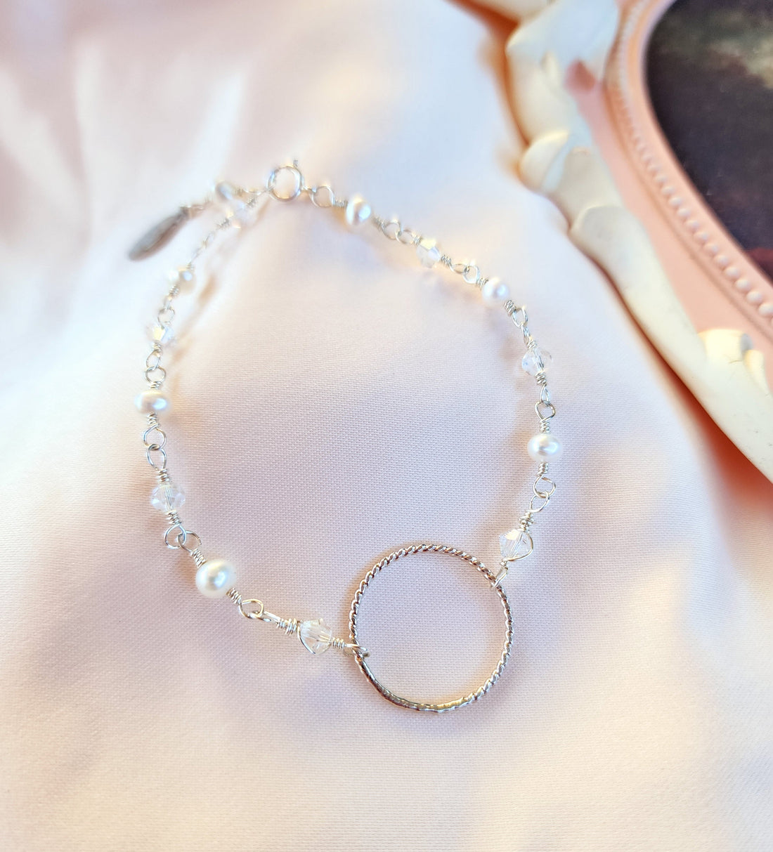 Top View of a hand linked bracelet with a twist ring pendant for a fun 90s geometric look